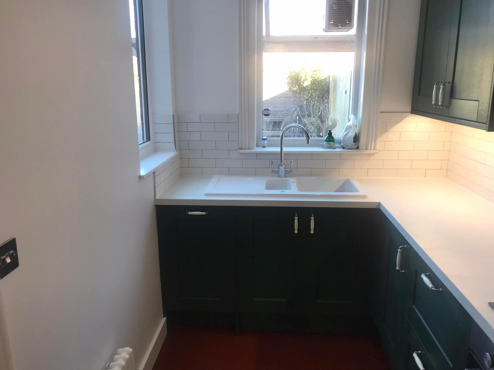 Green shaker kitchen with white worktop and subway tiles